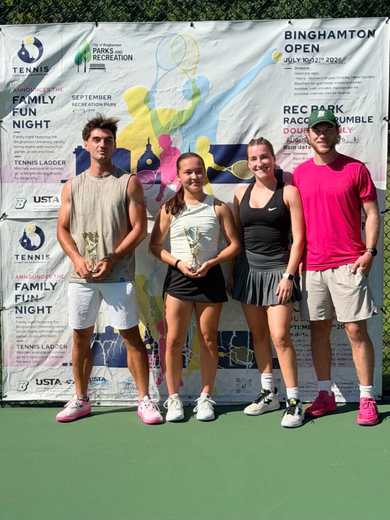 The four mixed doubles finalists stand with their trophies in front of the Rec Park Racquet Rumble banner